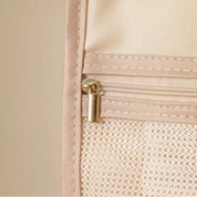 Beige travel pouch with gold zipper and visible brand logo on a beige background